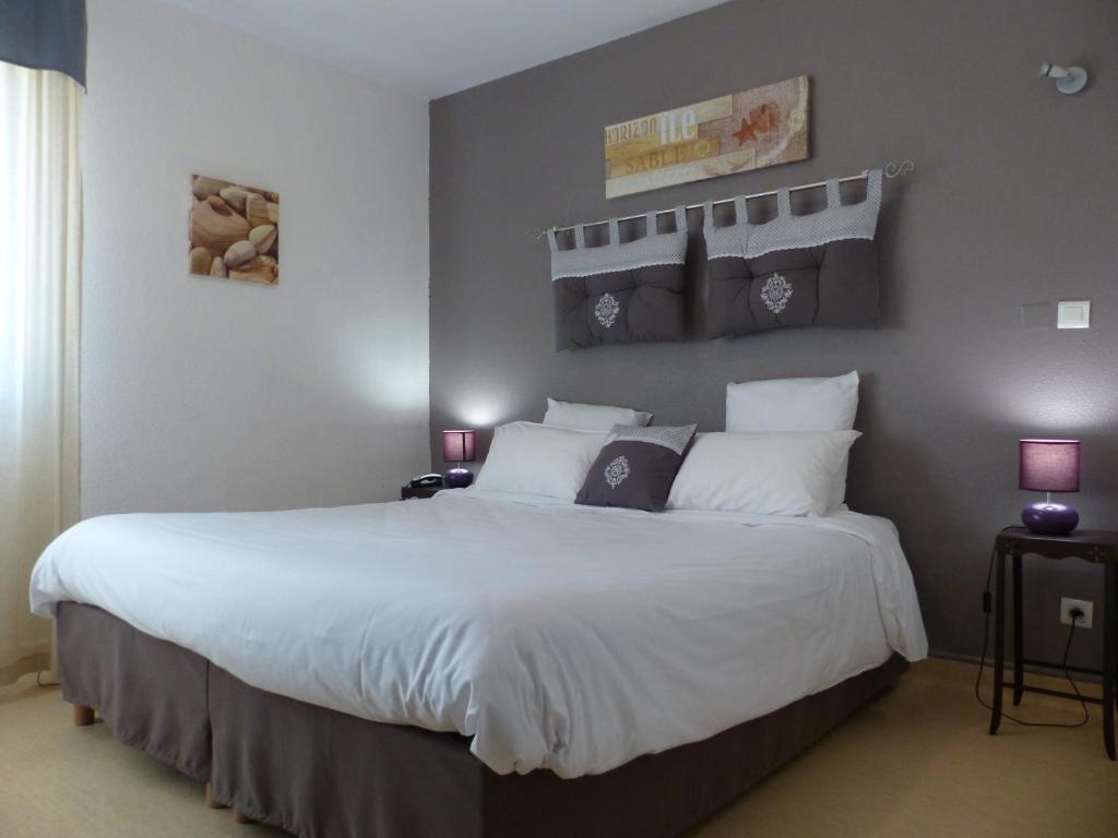 una camera da letto con un grande letto con lenzuola bianche di Le President-Gare Nimes Pont Du Gard a Bellegarde