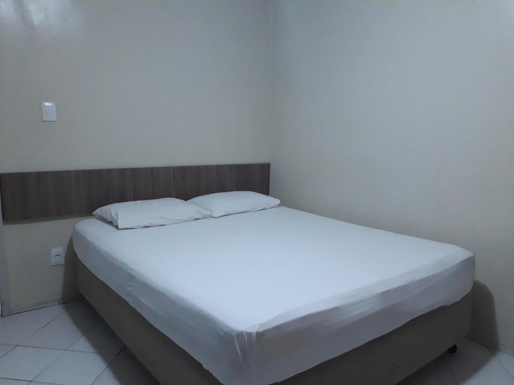 uma cama branca com duas almofadas em cima em Hotel Pio em Teresina