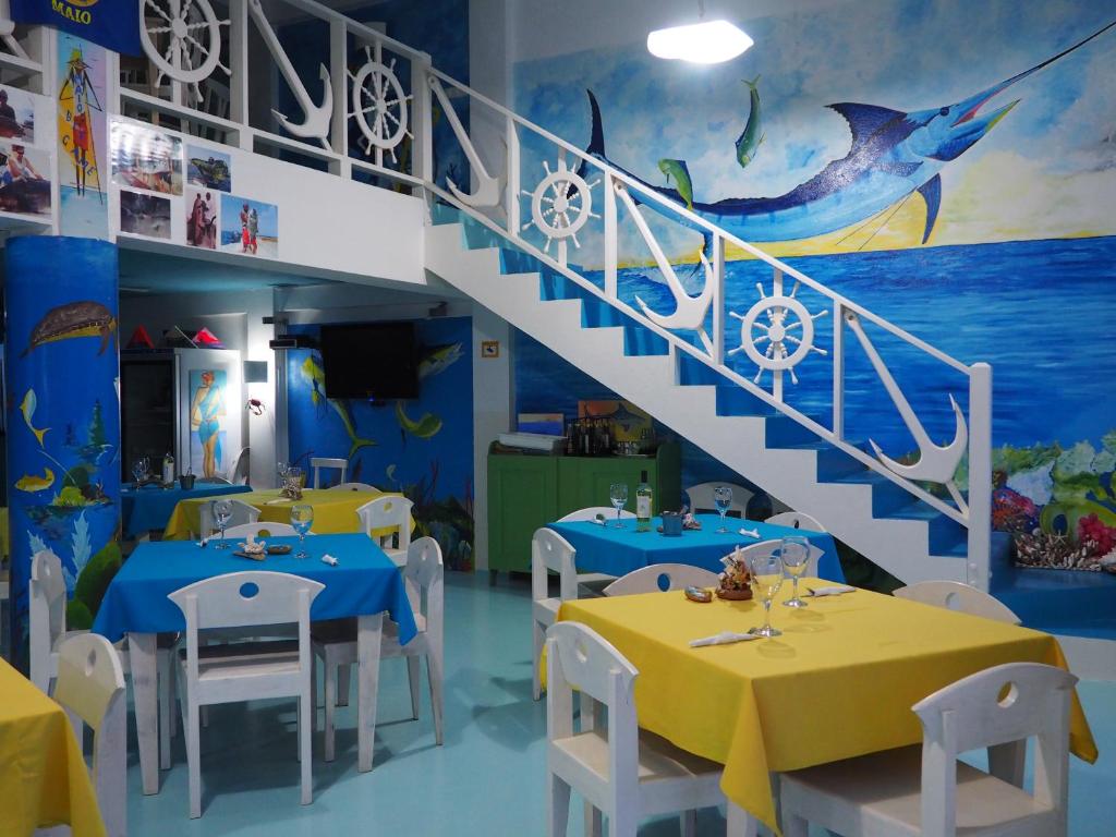 a restaurant with blue tables and white chairs and a staircase at Pensaò Big Game Maio in Vila do Maio