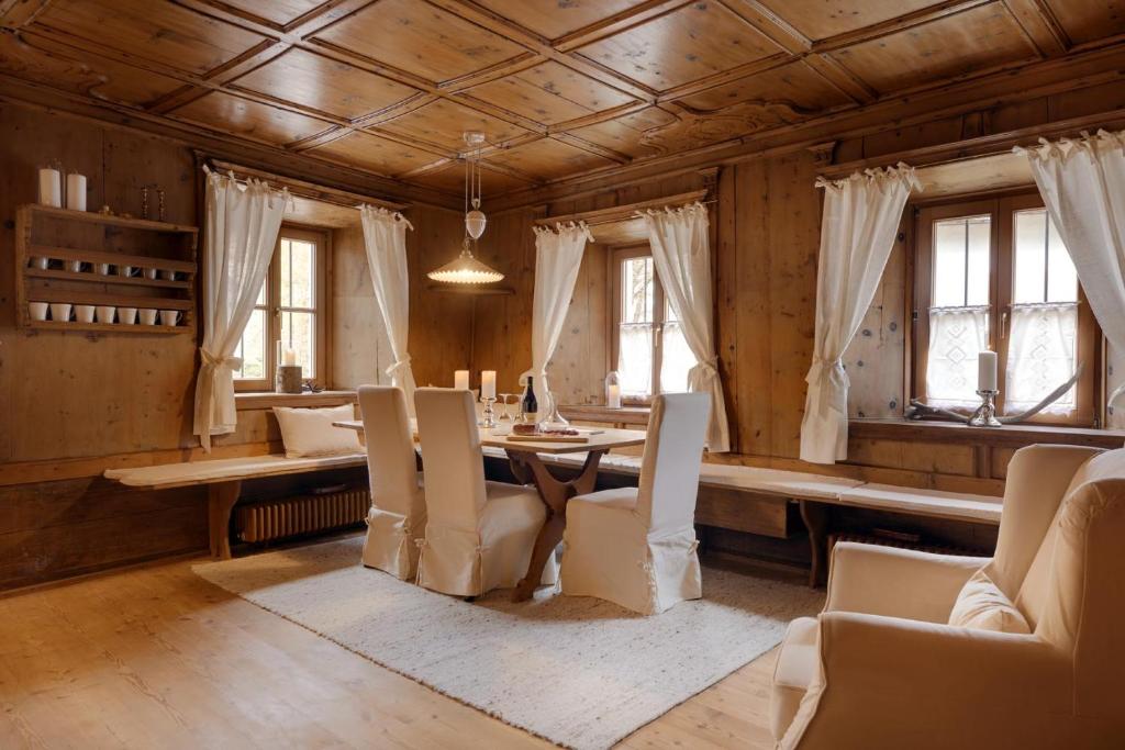 a dining room with a table and chairs and windows at Chaletapartement Ambiente Villa Mozart mit Sauna in Chienes