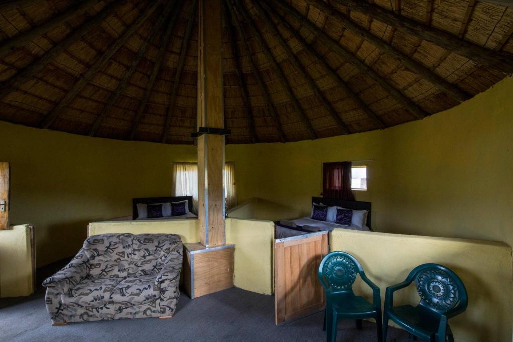 a bedroom with a bed and two chairs in a tent at Sani Stone Lodge in Mokhotlong