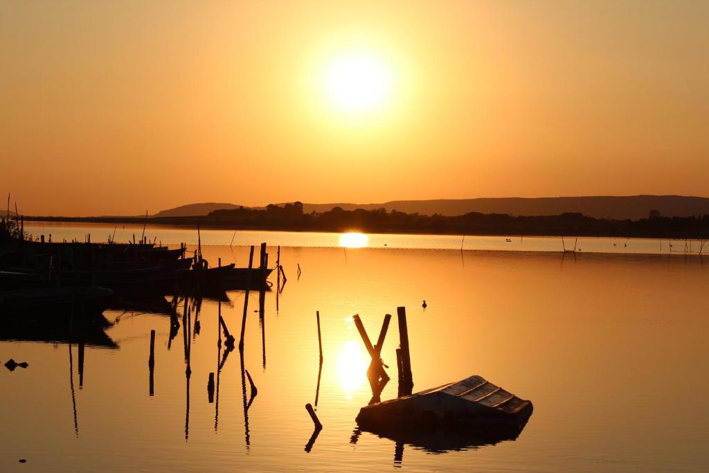 a sunset on a lake with a boat in the water at Studio 237 Port Camargue, Piscine, Climatisation, 2 personnes in Le Grau-du-Roi