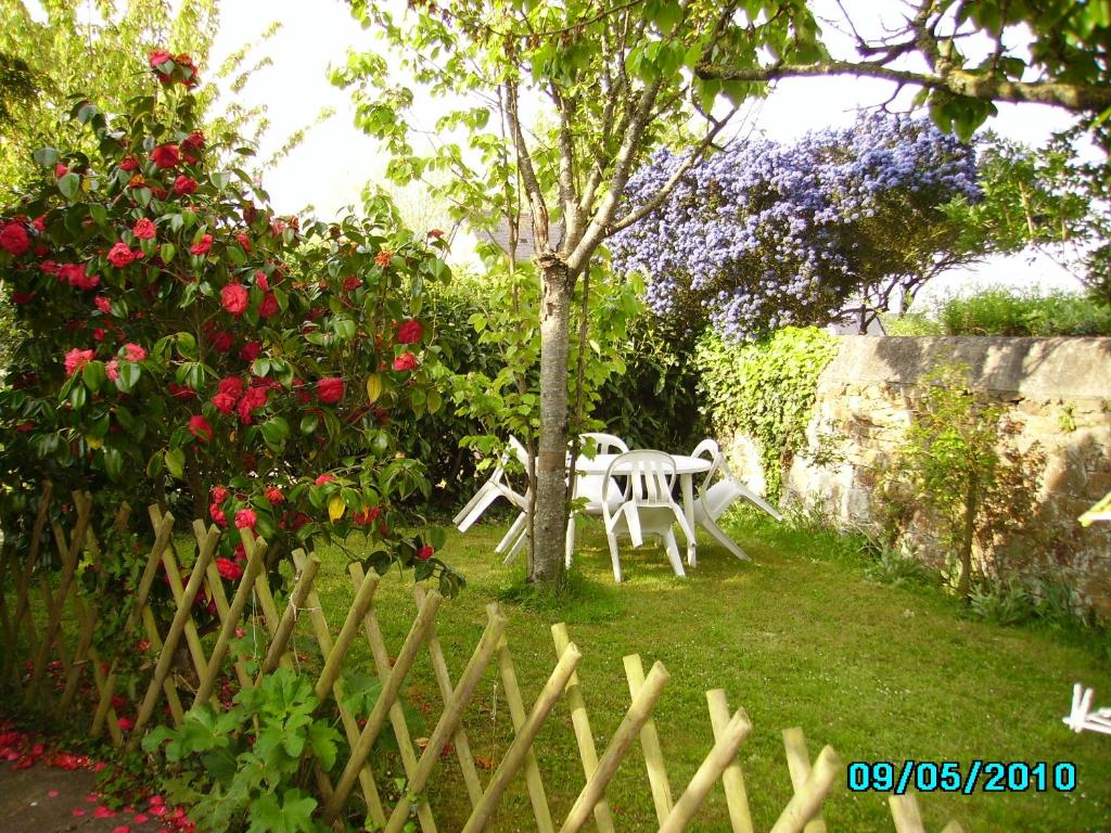 een witte tafel en stoel in een tuin met rozen bij Petite maison de vacances in Pléneuf-Val-André