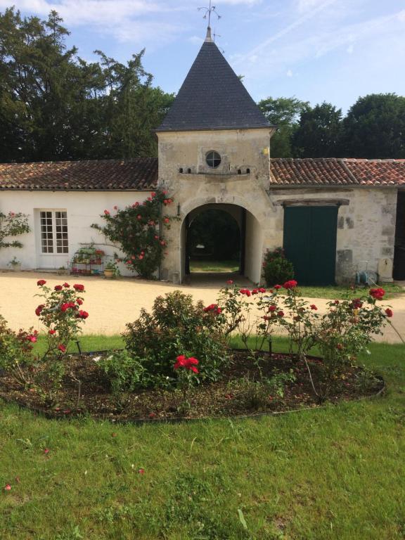 un vieux bâtiment avec un portail et des fleurs dans une cour dans l'établissement le Logis du Plessis, à Chaniers