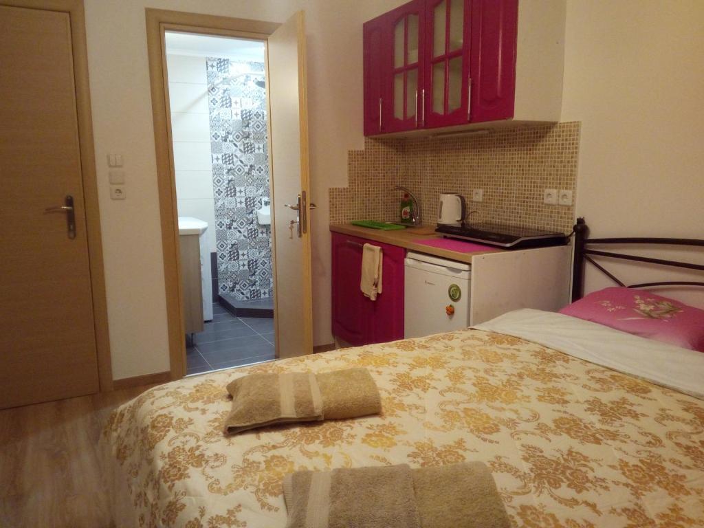 a bedroom with a bed and a kitchen with red cabinets at Comfortable inexpensive apartmets near metro in Athens