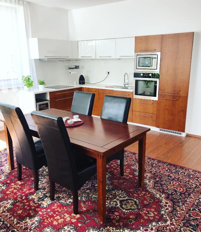 kuchnia z drewnianym stołem i czarnymi krzesłami w obiekcie Apartmans Les w Zlinie