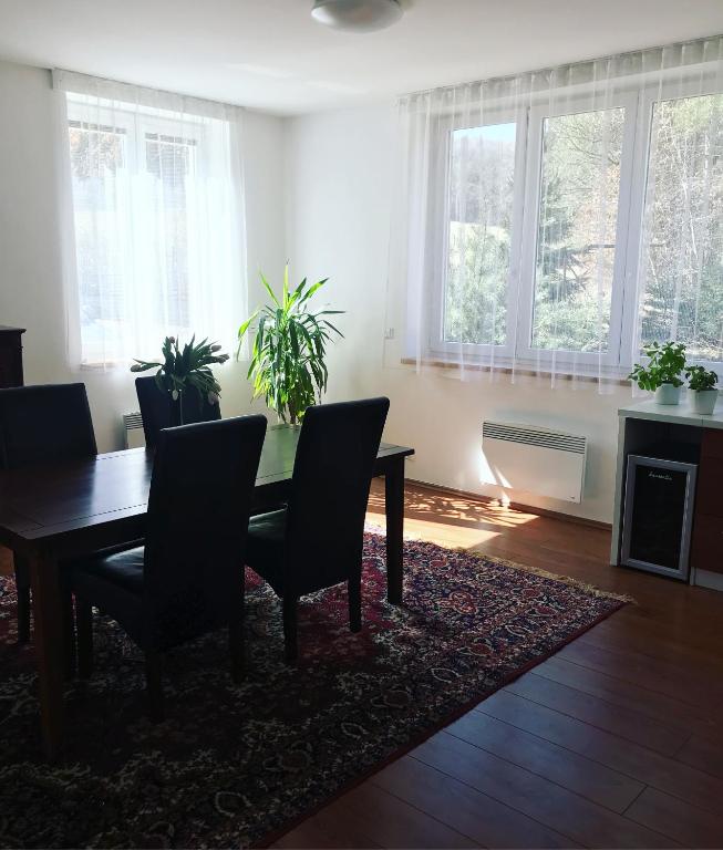 jadalnia ze stołem, krzesłami i oknami w obiekcie Apartmans Les w Zlinie