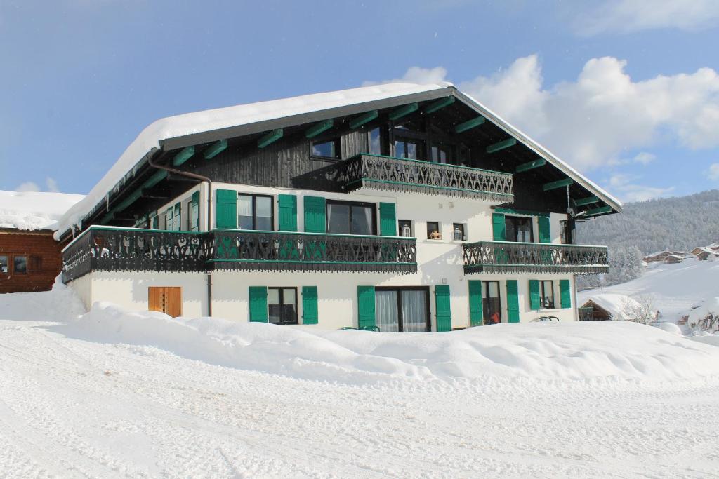 a snow covered house with a balcony in the snow at Chalet Fleur des Alpes in Les Gets