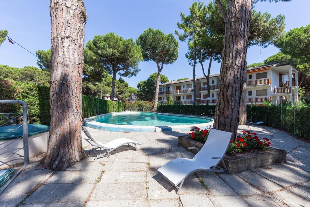 a swimming pool with two trees and two chairs at Residence Miami in Lido di Spina