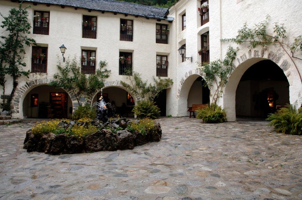 duży budynek z dziedzińcem z drzewami i roślinami w obiekcie Hotel Caldas w mieście Caldes de Boi
