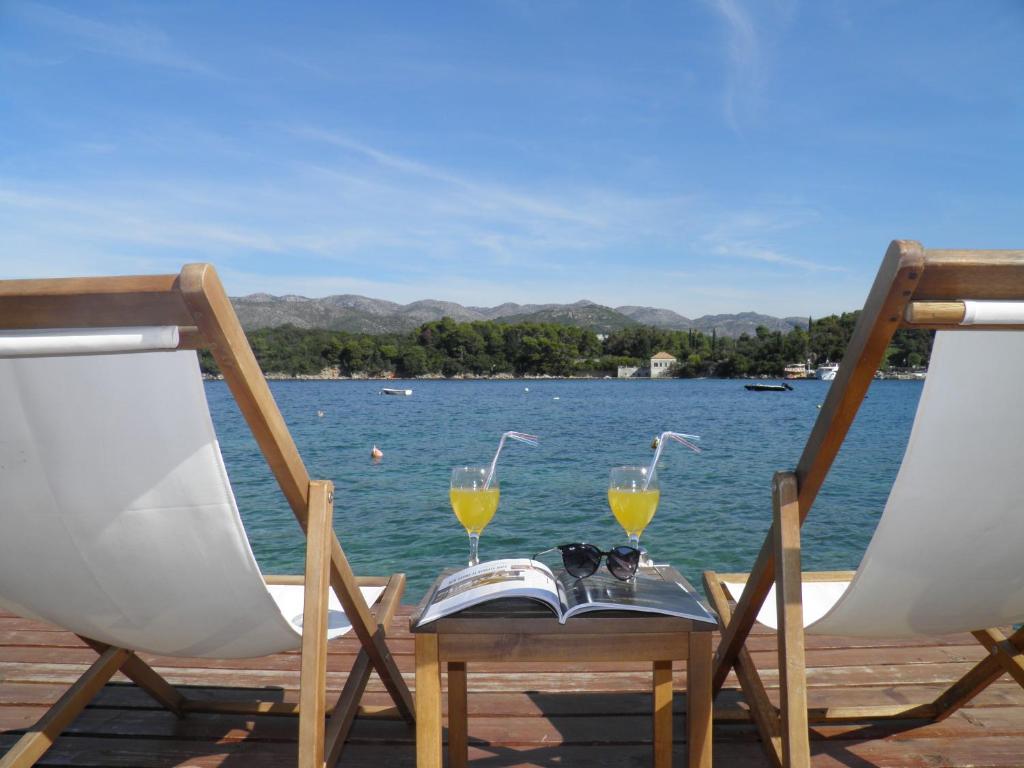 two chairs and two glasses on a table next to the water at Romantic apartment in Koločep