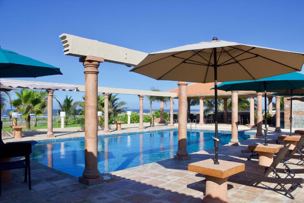 una piscina con sombrillas, mesas y sillas en Ananta Hotel, en Casitas
