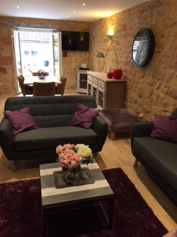 ein Wohnzimmer mit 2 Sofas und einem Tisch mit Blumen in der Unterkunft Le Nessmann in Sarlat-la-Canéda