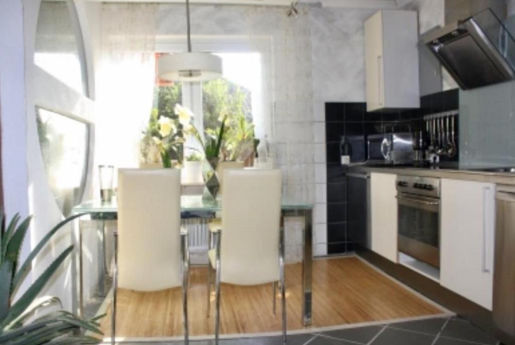 a kitchen with a glass table and white chairs at Ferienwohnung Villa Wohntraum in Varel