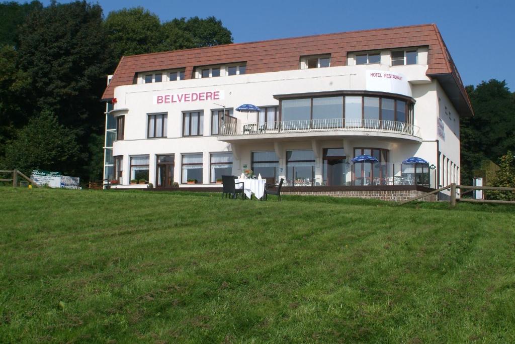 een groot wit gebouw bovenop een grasveld bij Hotel Belvedere in Heuvelland