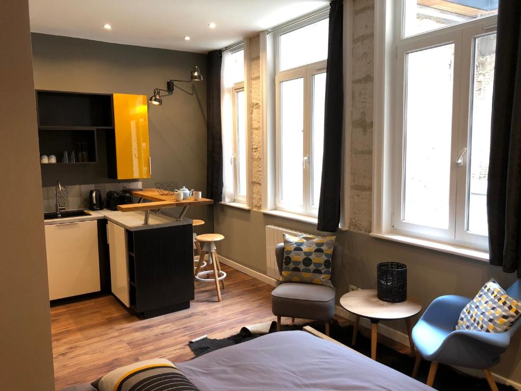 a room with a bed and a kitchen with windows at My Little Home - Le Vieux Lille de Rousseau in Lille
