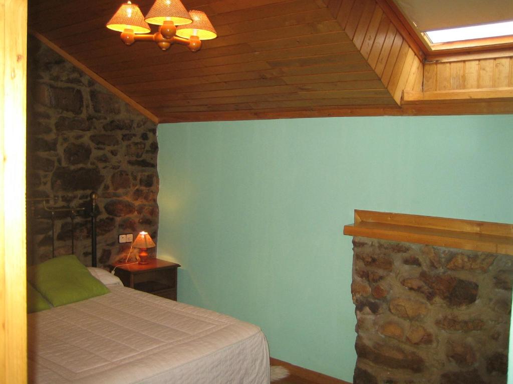 1 dormitorio con cama y pared de piedra en Apartamentos y Casas de Aldea La Pornacal en Villar de Vildas