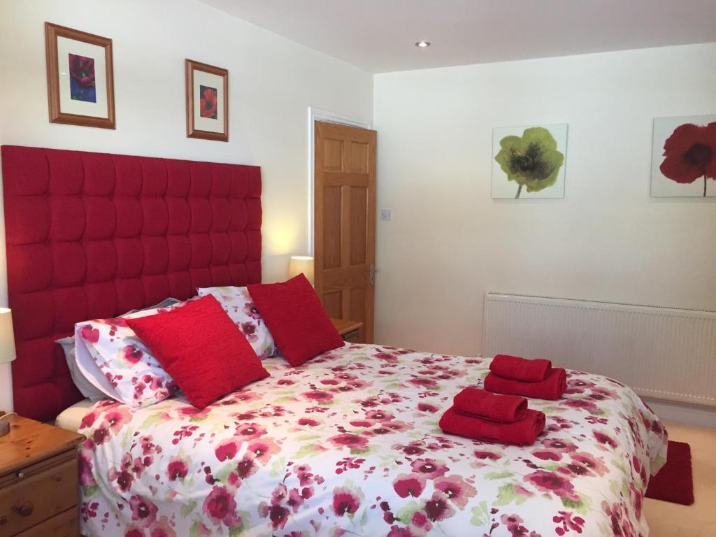 a bedroom with a large bed with red pillows at Little Gem in Weymouth