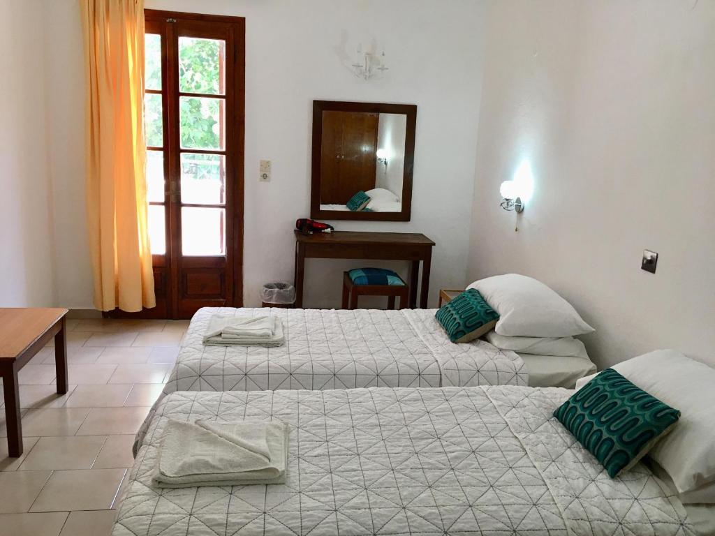 um quarto com 2 camas, uma mesa e um espelho em Poseidon Hotel em Kassiopi