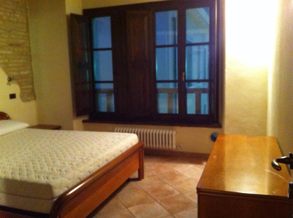 a bedroom with a bed and a table and a window at Residence LA FORTUNA in Fano
