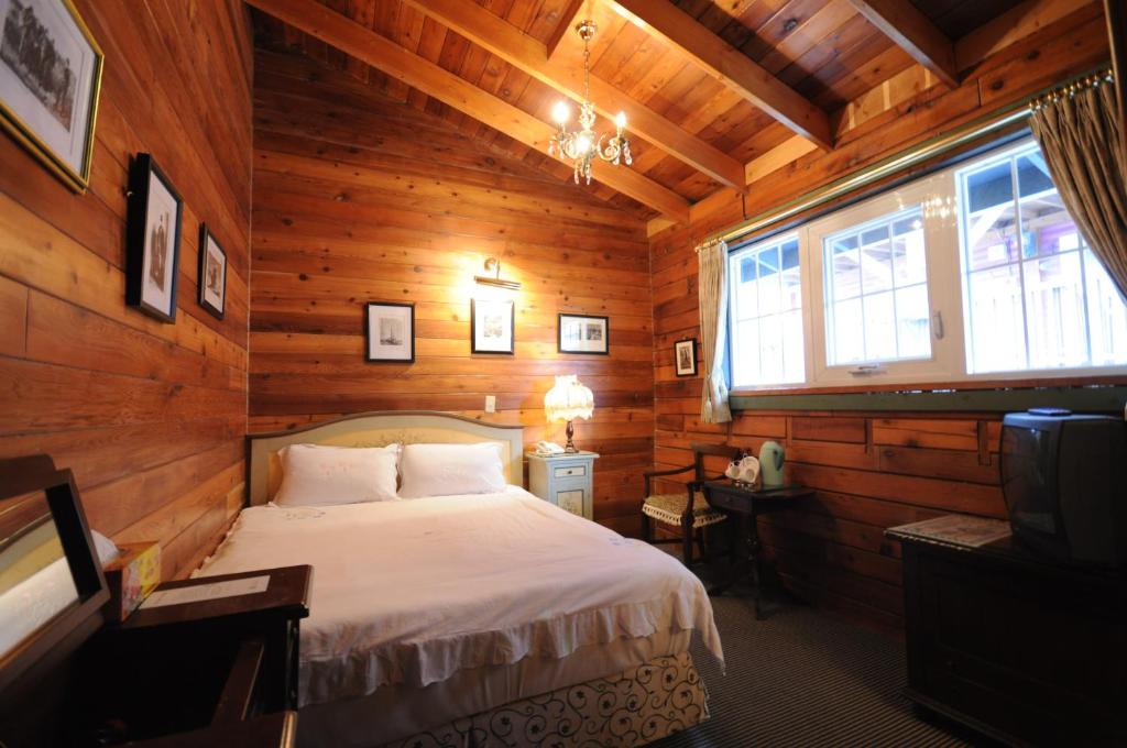 a bedroom with a bed in a wooden cabin at Cingjing Hanging Garden &amp; Resort in Ren&#39;ai