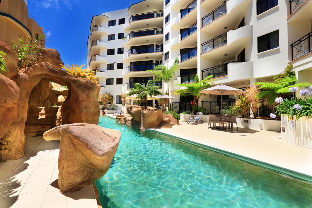 a swimming pool in front of a building at Caribbean Resort in Mooloolaba