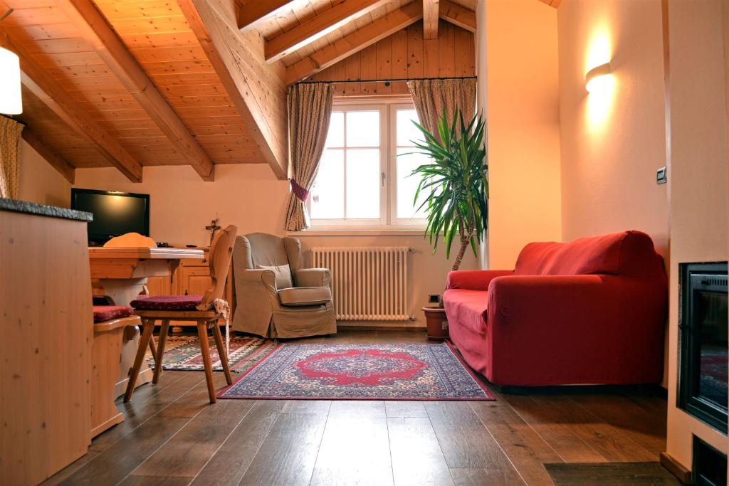 ein Wohnzimmer mit einem roten Sofa und Stühlen in der Unterkunft Casa Chatrian in Moena