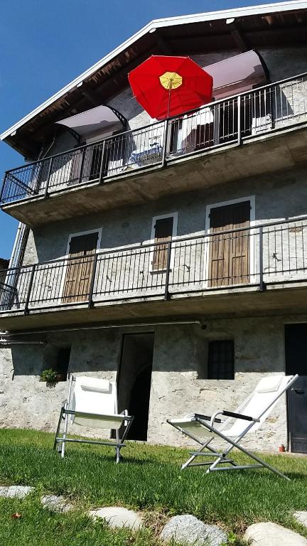 ein Gebäude mit zwei Stühlen und einem Balkon mit einem Sonnenschirm in der Unterkunft Piccola Perla A Livo in Livo