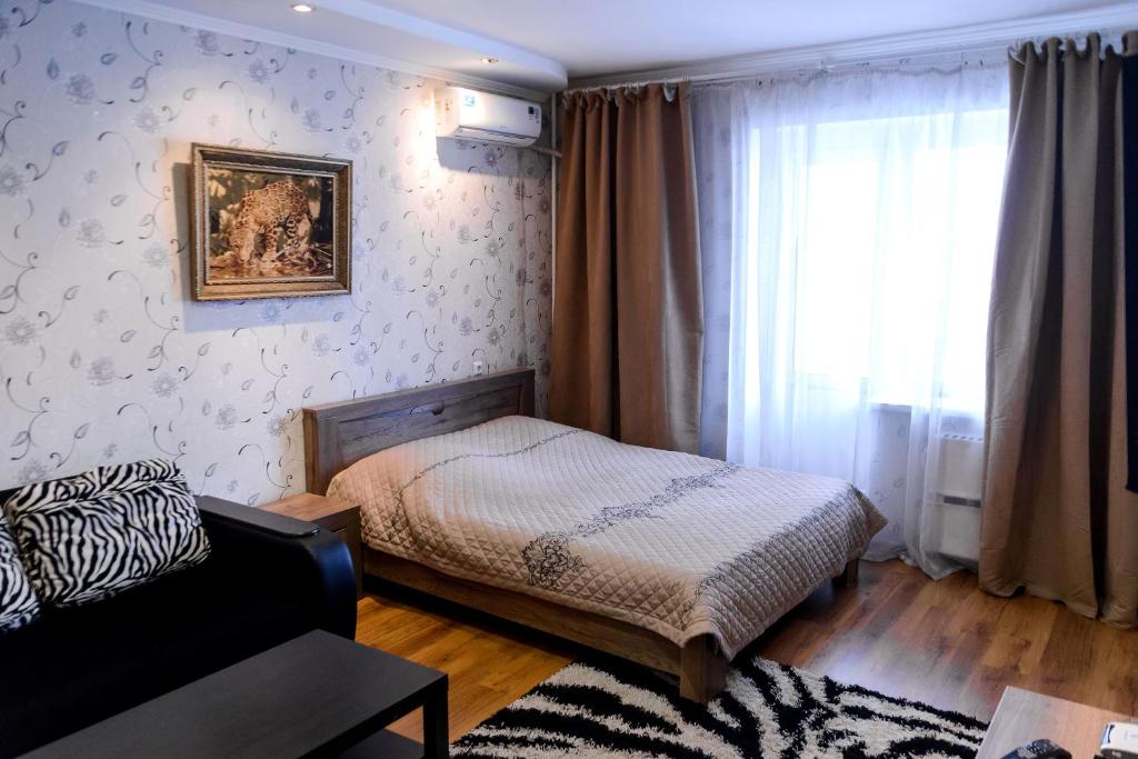 1 dormitorio con cama, sofá y ventana en ATLANT Apartments 214 en Voronezh