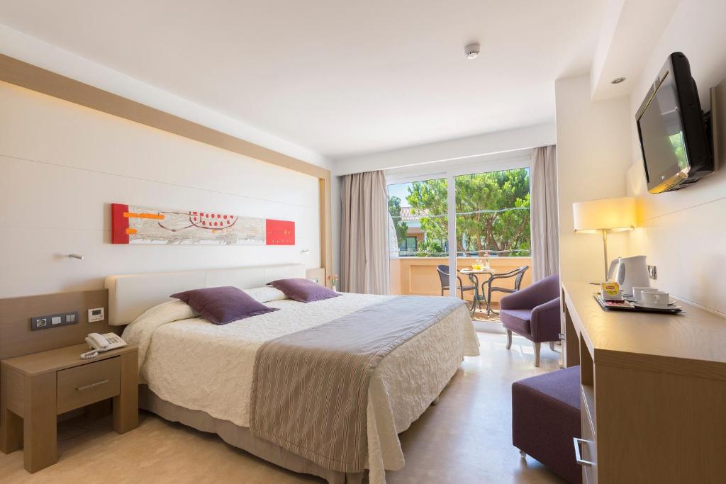 a hotel room with a bed and a desk with a television at Hipotels Playa La Barrosa - Adults Only in Chiclana de la Frontera
