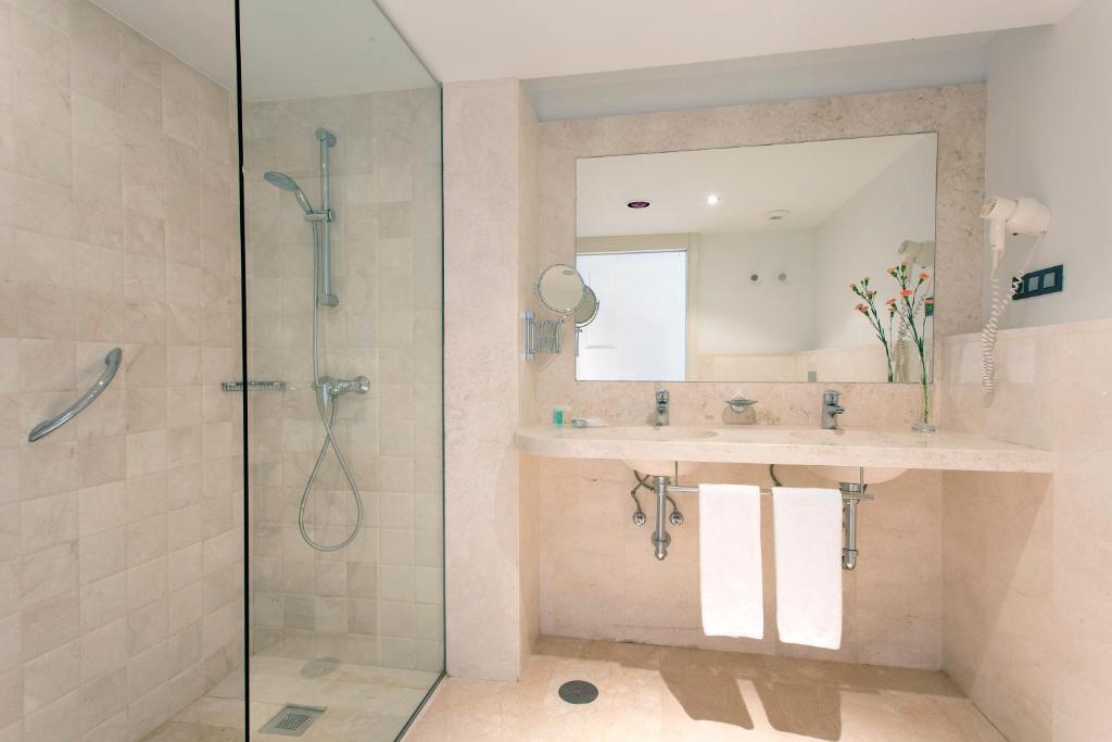 a bathroom with a shower and a sink and a mirror at Hipotels Playa La Barrosa - Adults Only in Chiclana de la Frontera