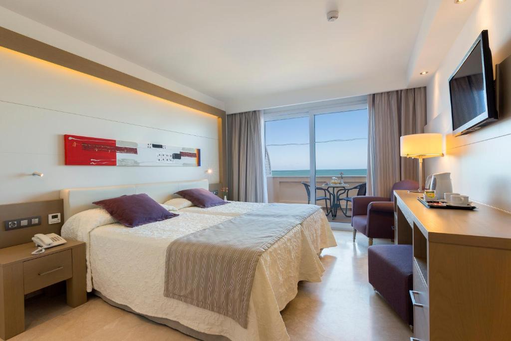a hotel room with a bed and a desk and a television at Hipotels Playa La Barrosa - Adults Only in Chiclana de la Frontera