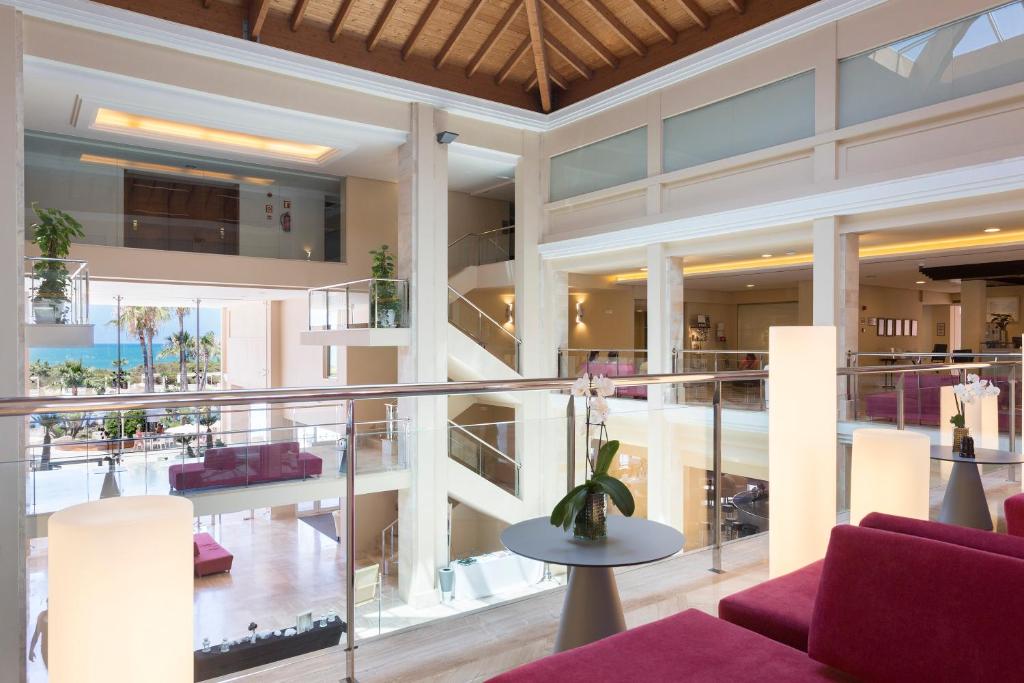 a large building with a balcony with purple furniture at Hipotels Playa La Barrosa - Adults Only in Chiclana de la Frontera