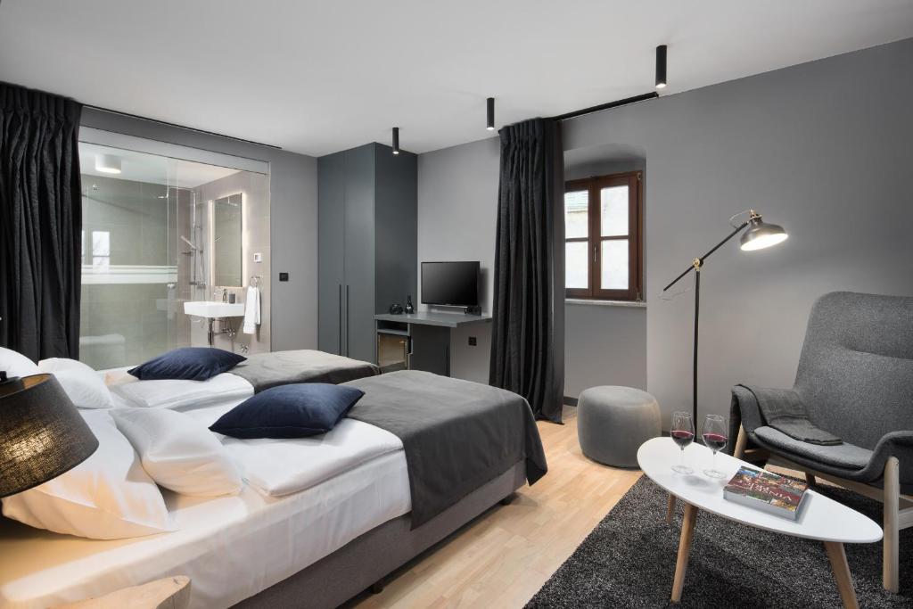 a bedroom with a large bed and a chair at Rialto Residence in Labin