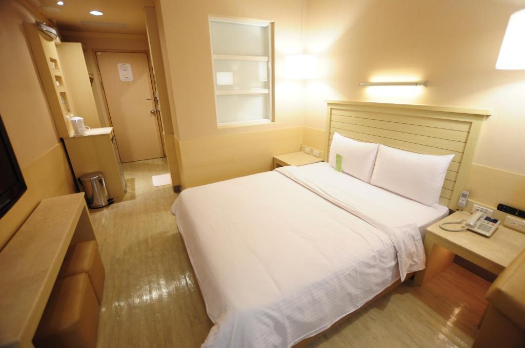 a bedroom with a large white bed and a window at Kindness Hotel - Jhong Jheng in Kaohsiung
