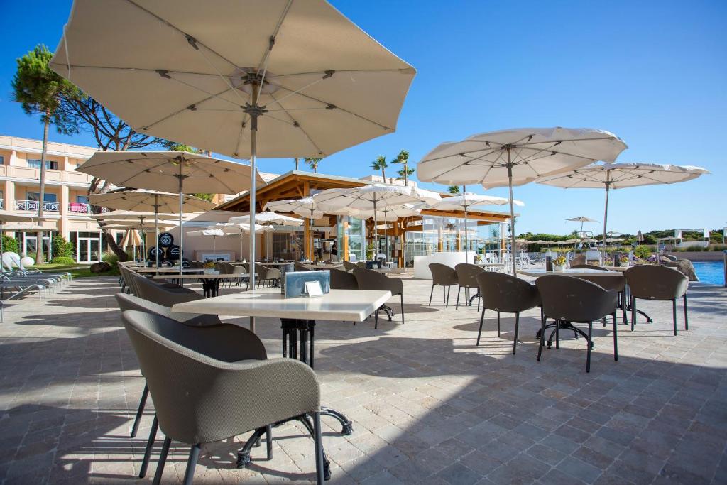 a patio with tables and chairs with umbrellas at Hipotels Playa La Barrosa - Adults Only in Chiclana de la Frontera