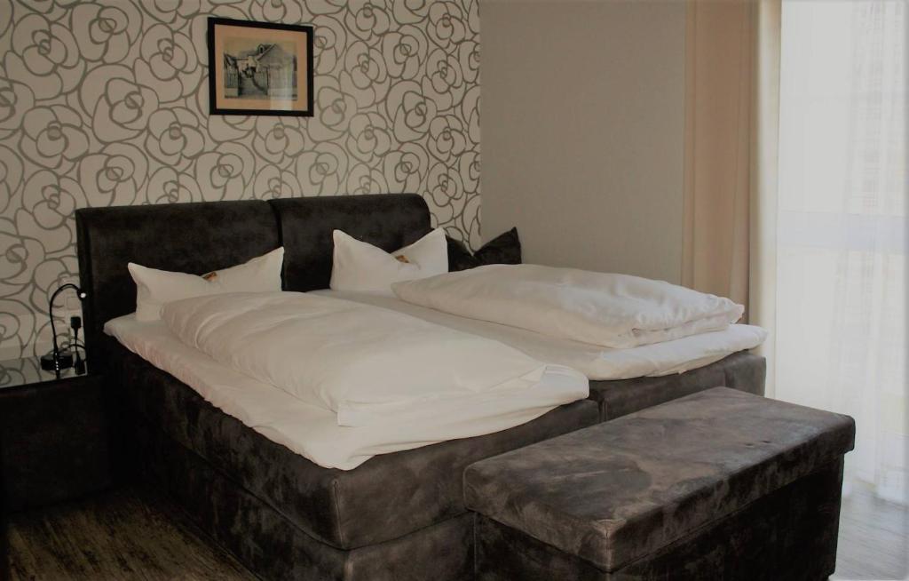 un letto con lenzuola bianche e uno sgabello in una camera da letto di Hotel Schöne Aussicht a Gießen