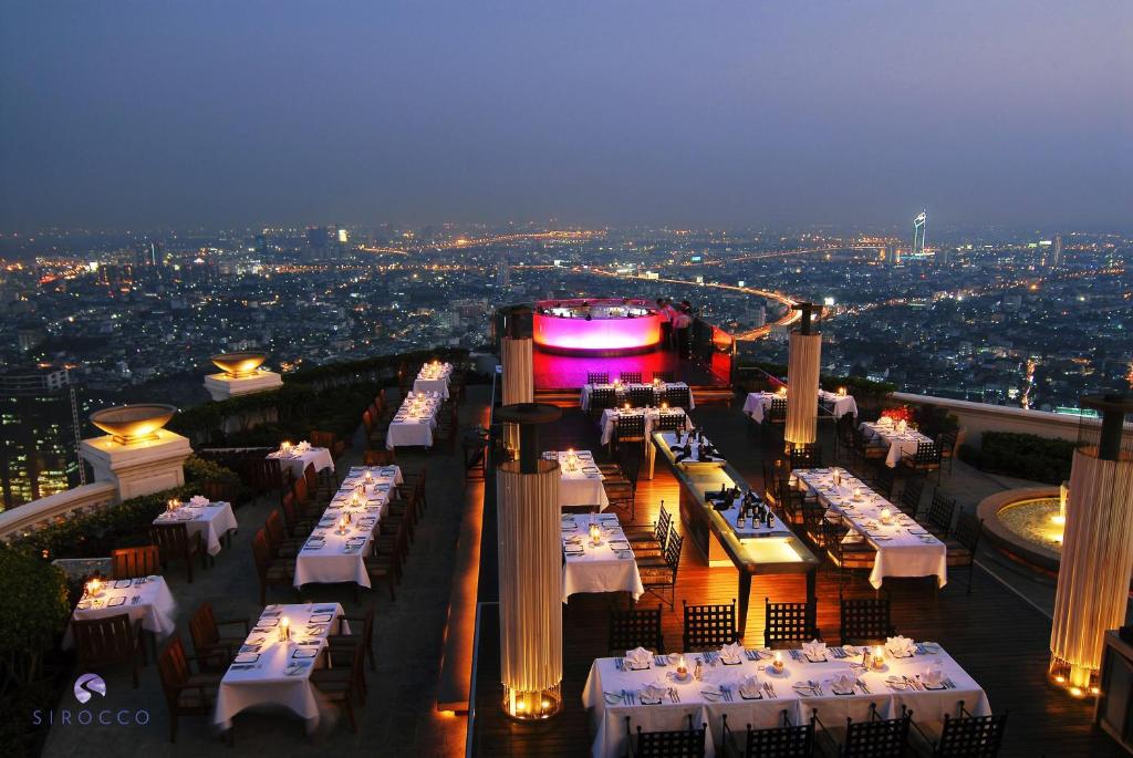a dining area with tables, chairs and umbrellas at lebua at State Tower in Bangkok