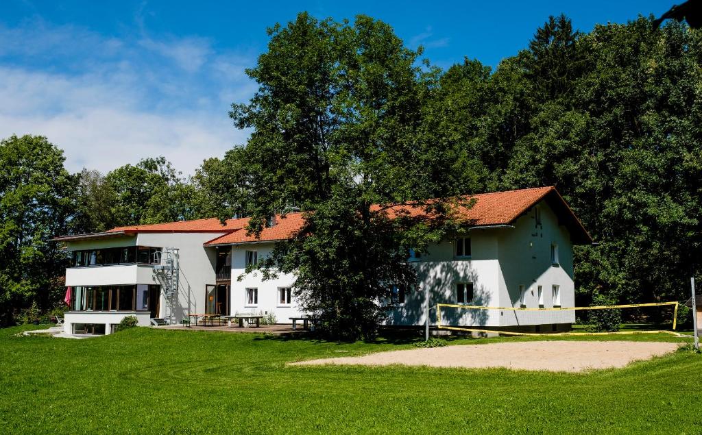 uma casa com uma árvore em frente a um campo em Jugendherberge Lenggries em Lenggries