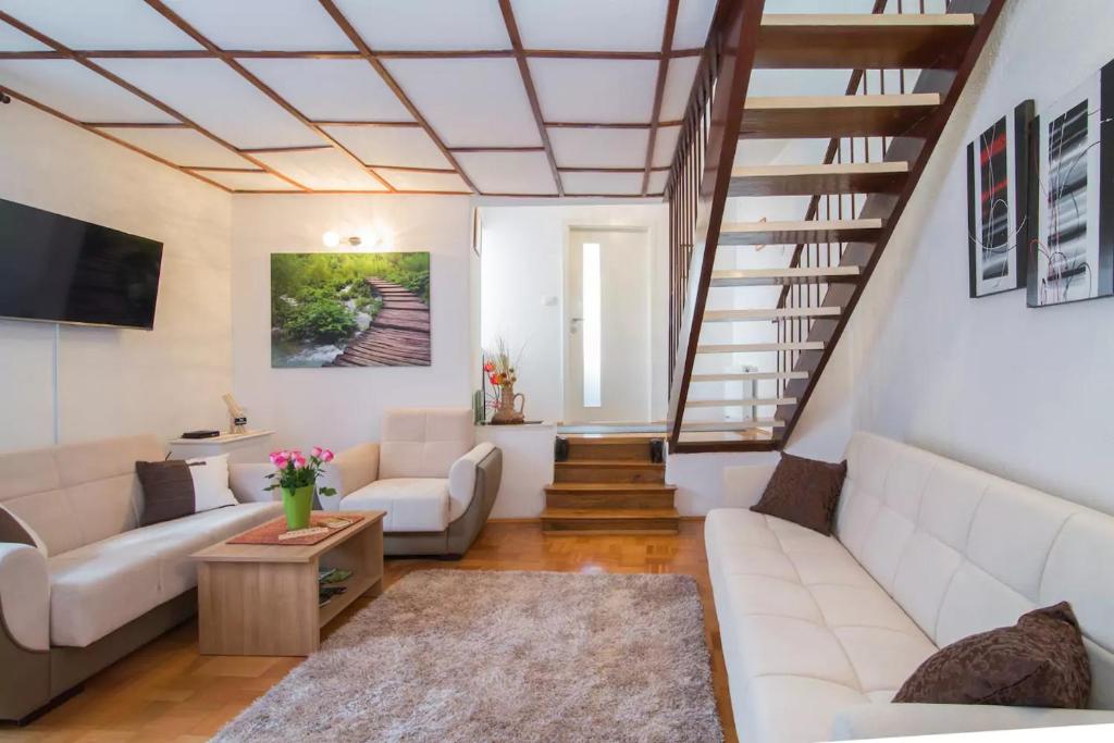 una sala de estar con muebles blancos y una escalera. en Charming Apartment, en Koper