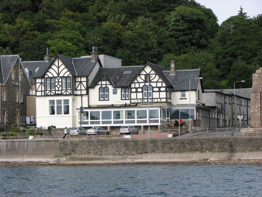 a large white and black building next to the water at Lancaster Hotel in Oban