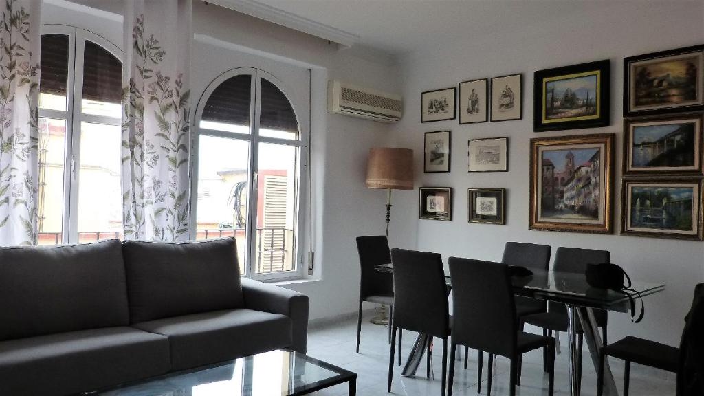 uma sala de estar com um sofá, uma mesa e cadeiras em La Casa De La Tia em Málaga