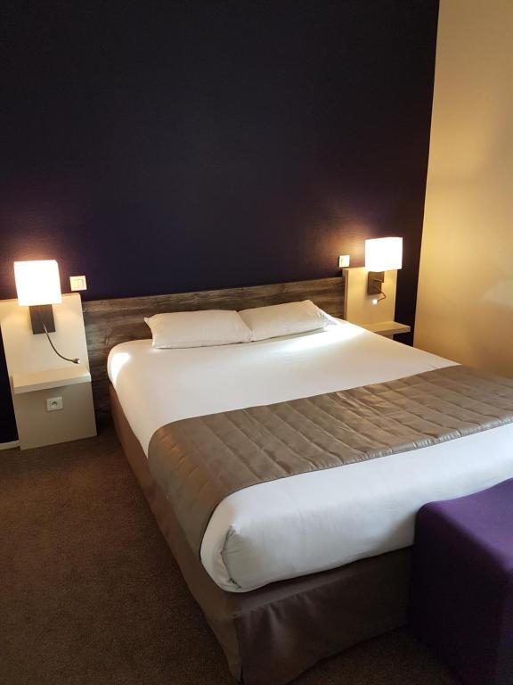 a bedroom with a large bed with two lamps at Le Corbeau in Auxonne