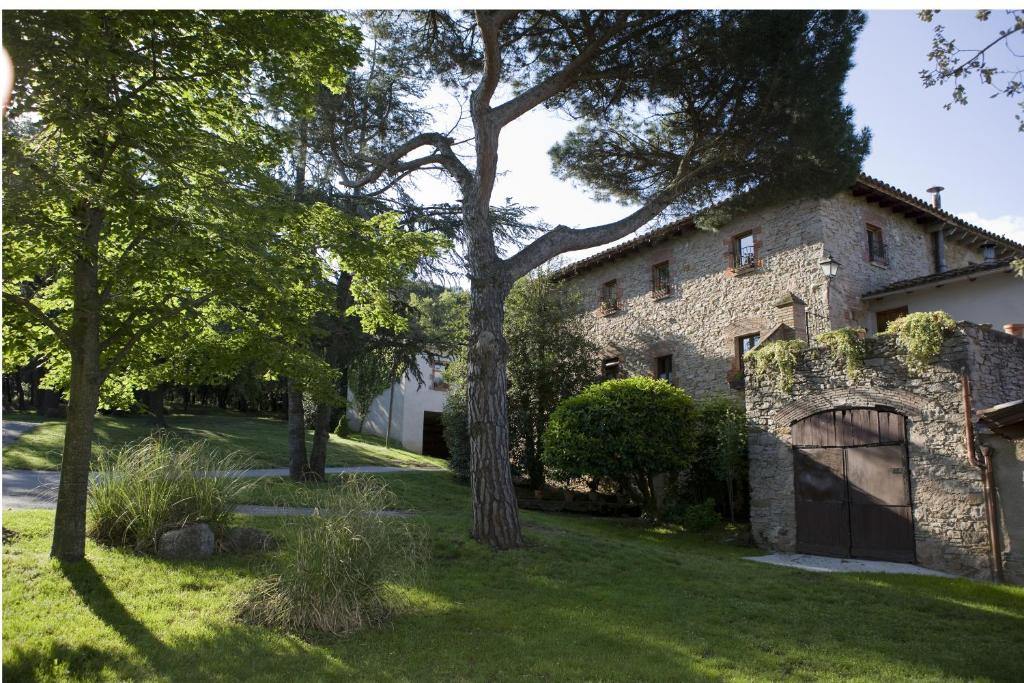 an old stone house with a tree in the yard at Mas Pratsevall in Taradell