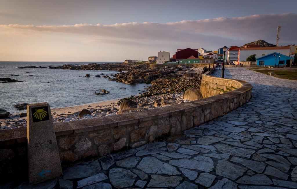 un camino de piedra junto a una playa con el océano en Apartamentos Muxia Mare, en Muxía