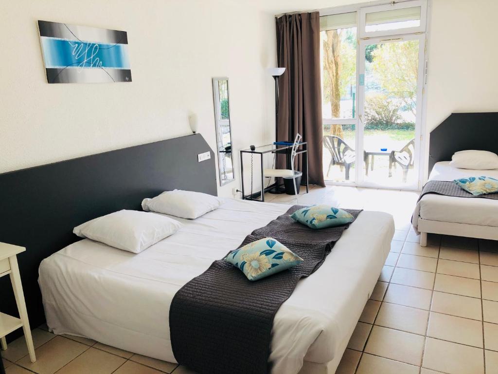 a hotel room with two beds and a window at Le Clos des Bruyères in Vallon-Pont-dʼArc