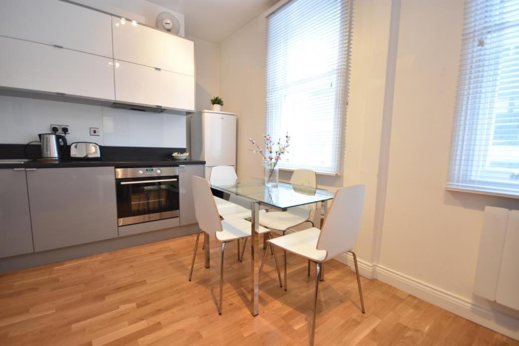 ロンドンにあるApt 2, Soho Apartments 1st floor by Indigo Flatsのキッチン(ガラステーブル、白い椅子付)