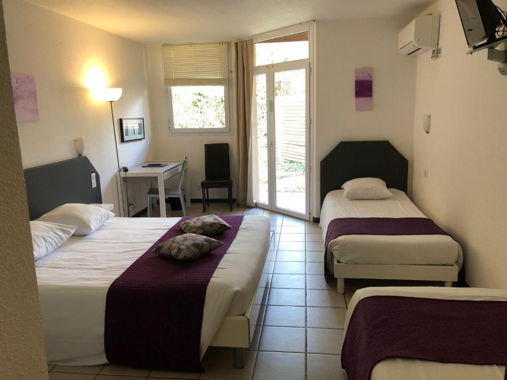 a hotel room with two beds and a desk and a room at Le Clos des Bruyères in Vallon-Pont-dʼArc