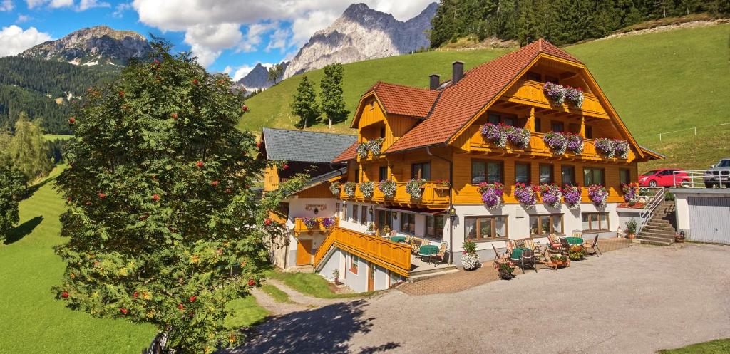 a large house with flowers on the balconies of it at Pension Bartlbauer in Ramsau am Dachstein