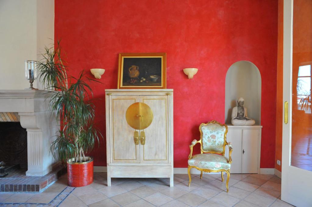 a room with a red wall with a cabinet and a chair at Villa Valflor chambres d'hôtes et appartements in Marseille